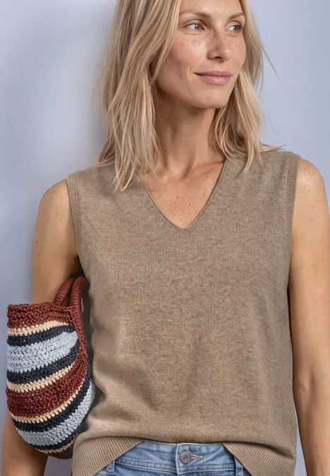 Pullunder mit V-Neck in Unifarbe sanded amber mel. Frau in beigem Ärmellosen Pullover und Jeans hält eine mehrfarbige Strohtasche.