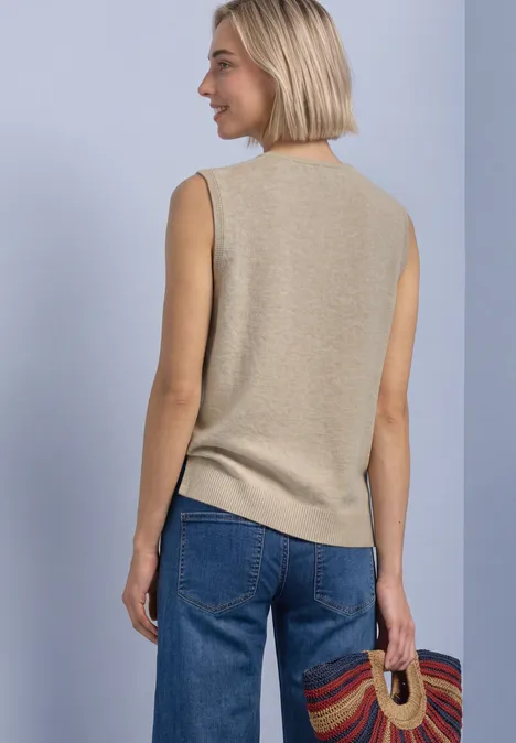 Pullunder mit V-Neck in Unifarbe light sepia sand mel. Frau von hinten trägt ein beiges ärmelloses Top, blaue Jeans und hält einen bunten Korb.