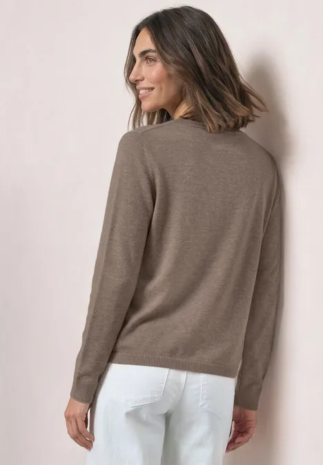 Basic Pullover mit U-Boot-Ausschnitt sanded amber mel. Frau im braunen Pullover und weißer Hose blickt über die Schulter und lächelt.