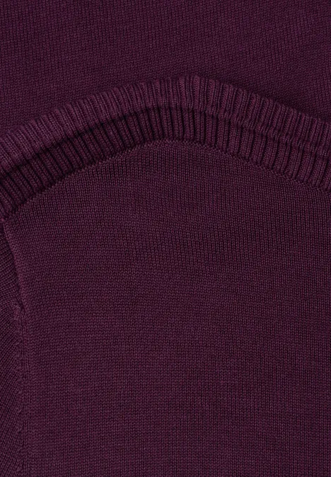 Nahaufnahme eines dunkelvioletten Strickstoffs mit geripptem Bund und sichtbarer Naht.