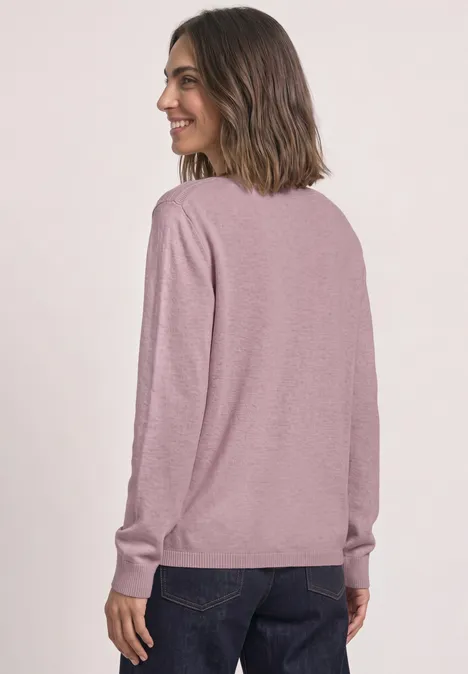 Sweter Basic z dekoltem w łódkę quiet rose mel. Kobieta od tyłu, różowy sweter z długim rękawem i ciemne dżinsy, uśmiecha się bokiem.