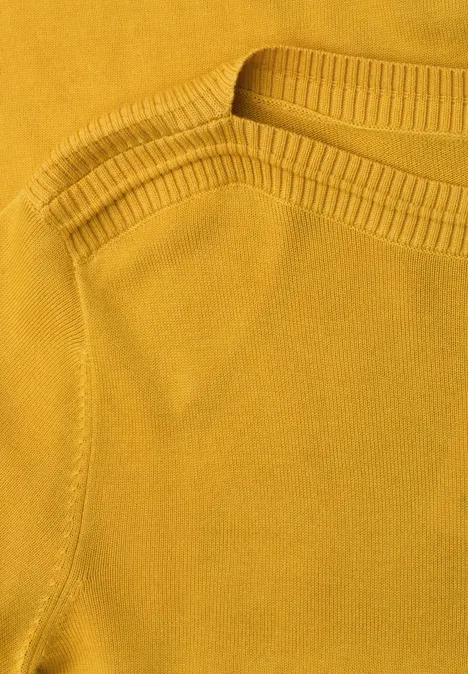 Nahaufnahme eines senfgelben Strickoberteils mit Rundhalsausschnitt und feiner Struktur.