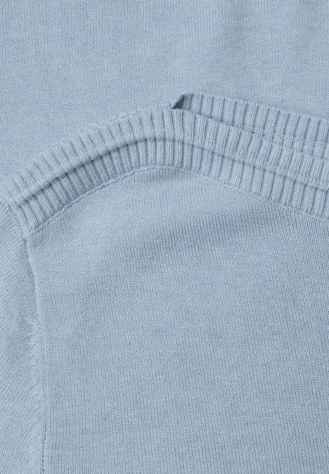 Nahaufnahme eines hellblauen Strickpullovers mit Rippenkante und sichtbarer Naht