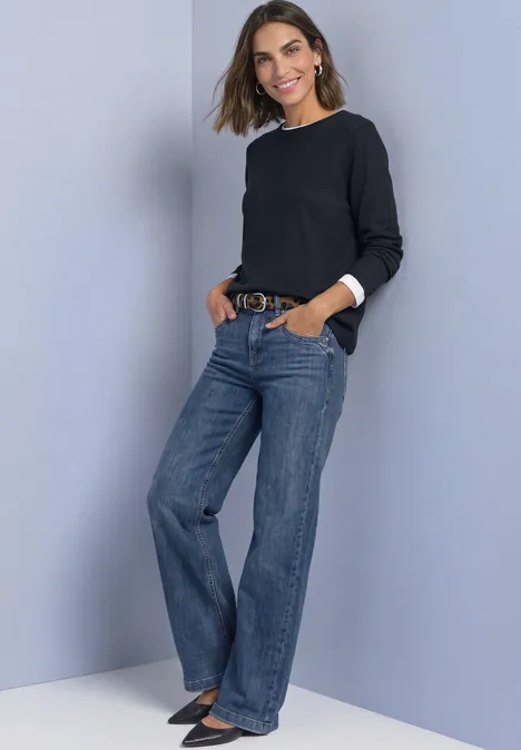 Pullover mit Rundhals und Rollkanten darkest blue Frau in schwarzem Pullover und weit geschnittenen Jeans posiert lächelnd mit Händen in den Taschen.