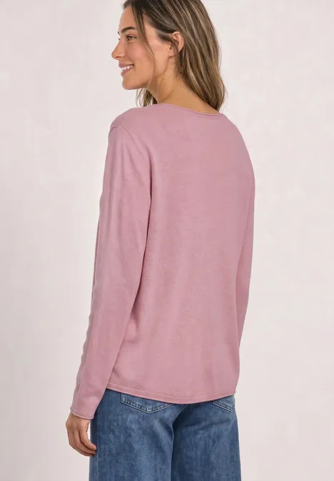 Pullover mit Rundhals und Rollkanten vintage blush mel. Eine Frau in rosa Langarmshirt und blauen Jeans steht seitlich, lächelt.