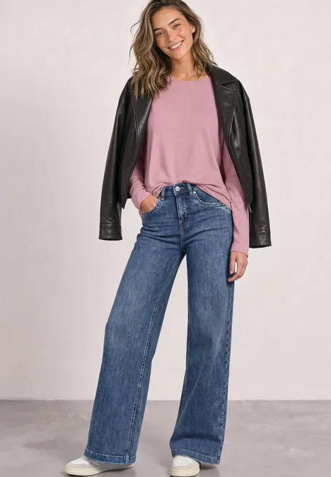 Pullover mit Rundhals und Rollkanten vintage blush mel. Lächelnde Frau in rosa Pullover, weiten Jeans und schwarzer Lederjacke vor neutralem Hintergrund.