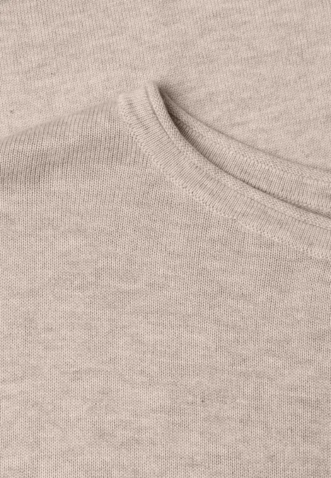 Nahaufnahme eines beigen T-Shirts mit Rundhalsausschnitt und feiner Strickstruktur.