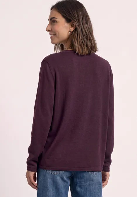 Frau von hinten in blauen Jeans und dunkelviolettem Langarmpullover.