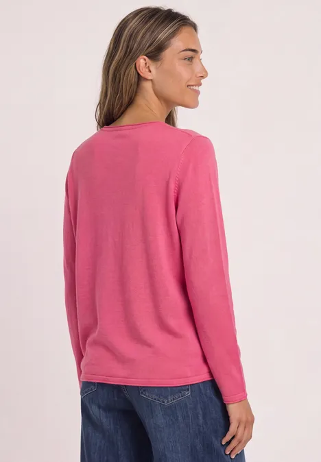 Frau von hinten mit rosa Langarmshirt und dunkler Jeans vor hellem Hintergrund.