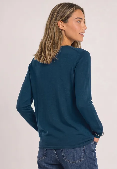 Pullover mit Rundhals und Rollkanten blue petrol Frau von hinten in lässigem dunkelgrünem Langarmshirt und Jeans, eine Hand in der Hosentasche.