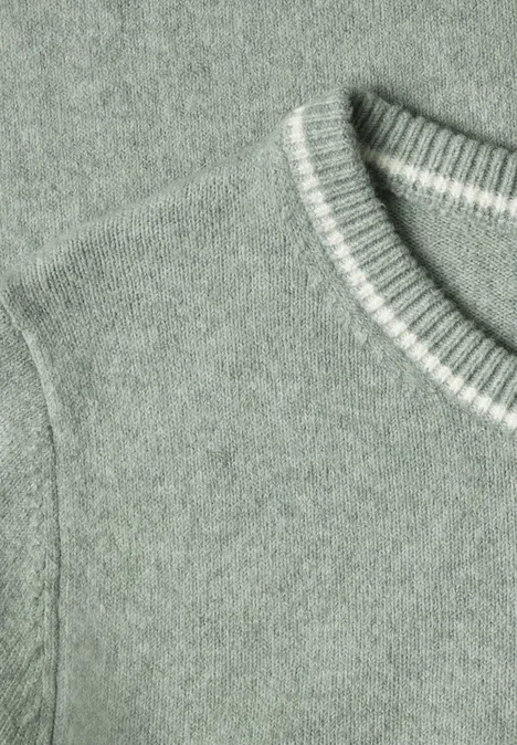 Nahaufnahme eines grünen Strickpullovers mit Rundhalsausschnitt und gerippten Bündchen.