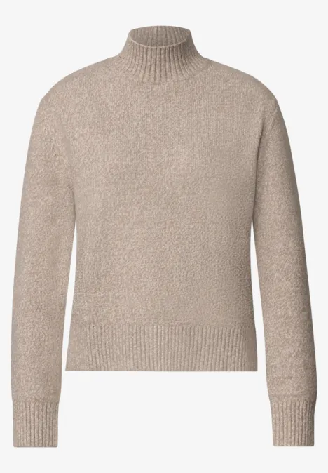 Pull à col roulé beige en maille douce avec manches longues.