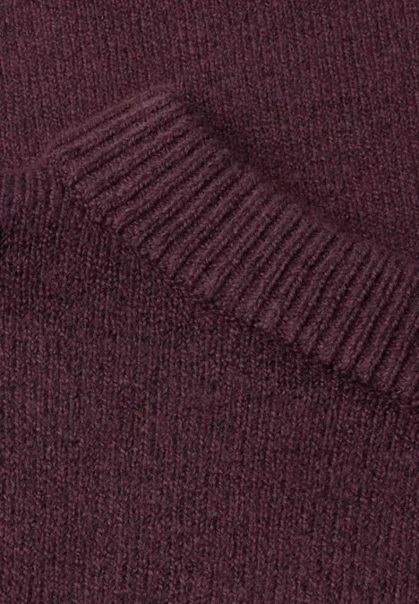 Gros plan d’un pull en maille bordeaux avec col côtelé.