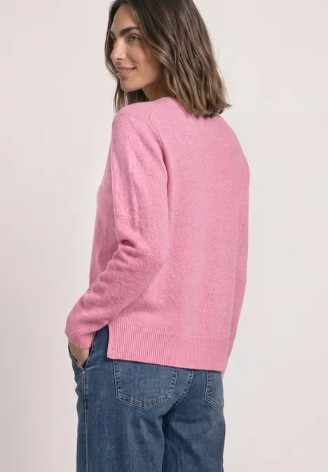 Frau in rosa Pullover und Jeans, von hinten gezeigt, lächelnd, lockeres Styling.