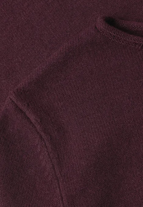 Nahaufnahme eines burgundroten Strickpullovers mit Schulterpartie und angerauter Textur.