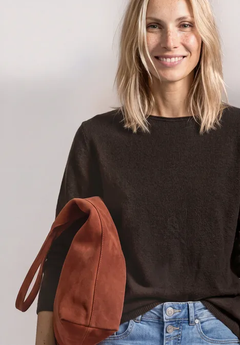 Trui met bootnek en omgeslagen randen black coffee Lachende blonde vrouw in donkerbruin truitje met een roestkleurige tas