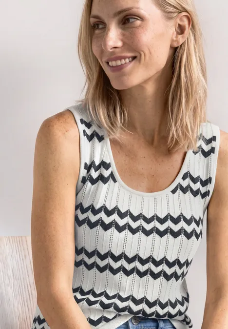 Strick-Top mit Zick-Zack-Muster off white Eine lächelnde Frau in einem ärmellosen, schwarz-weißen Top mit Zickzackmuster.