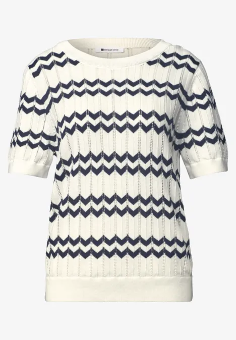 Weißer Kurzarm-Pullover mit Wellen-Zopfstrick und dunkelblauen Zickzackstreifen.