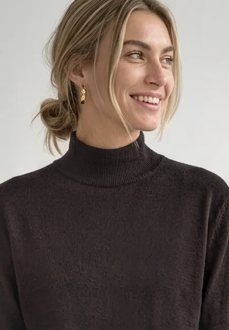Pull basique à col roulé black coffee Femme souriante, chignon, pull à col roulé marron.