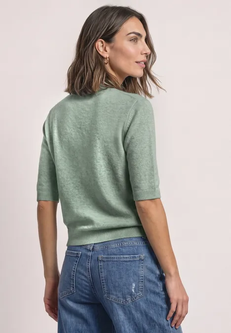 Kurzarm Pullover mit Turtle Neck eucalyptus green mel. Frau im Profil mit grünem Halbarm-Pullover und blauen Jeans vor neutralem Hintergrund.