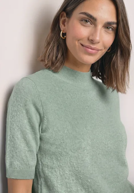 Kurzarm Pullover mit Turtle Neck eucalyptus green mel. Eine lächelnde Frau mit schulterlangen dunklen Haaren in einem kurzärmeligen, hellgrünen Pullover.