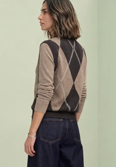 Pullunder mit Rundhals und Argyle-Muster sanded amber mel. Seitenansicht einer Frau mit argyle Pullunder und dunkler Jeans vor hellgrünem Hintergrund.