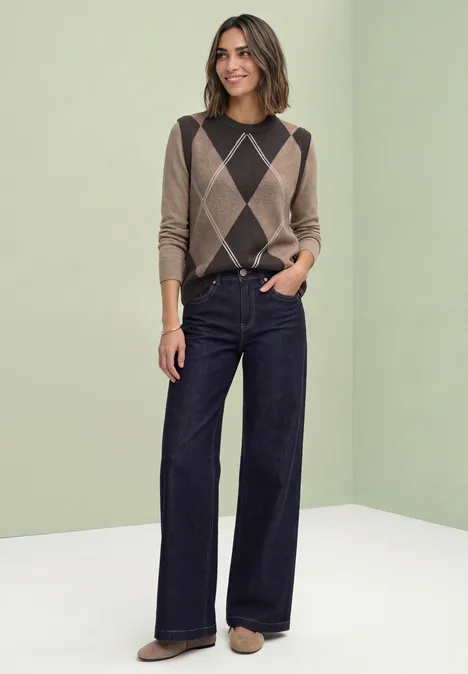 Pullunder mit Rundhals und Argyle-Muster sanded amber mel. Frau trägt braunen Rautenmuster-Pullover und dunkelblaue, weite Jeans vor hellem Hintergrund.