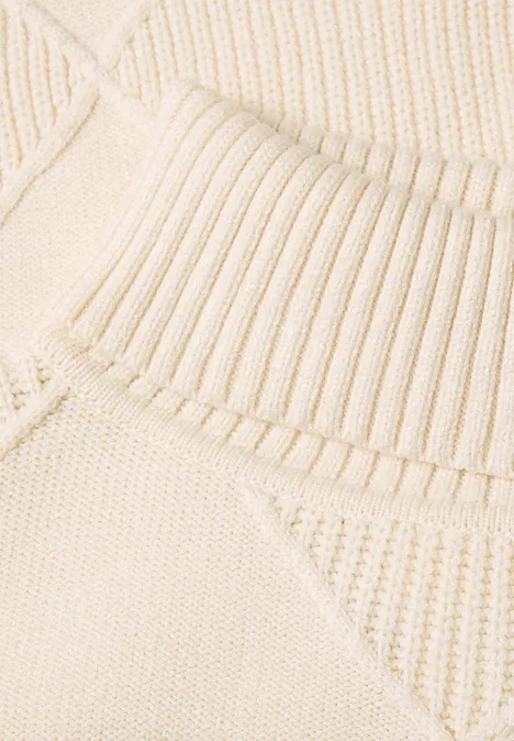 Nahaufnahme eines cremefarbenen Strickpullovers mit Rippkragen und strukturiertem Muster.