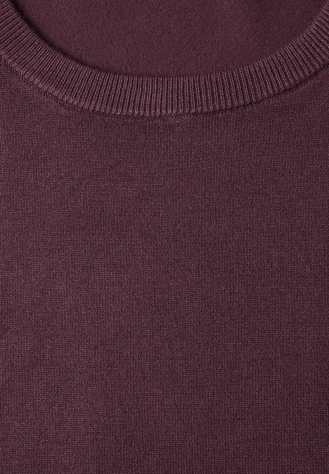 Gros plan d’une encolure ronde bordeaux d’un pull en maille.