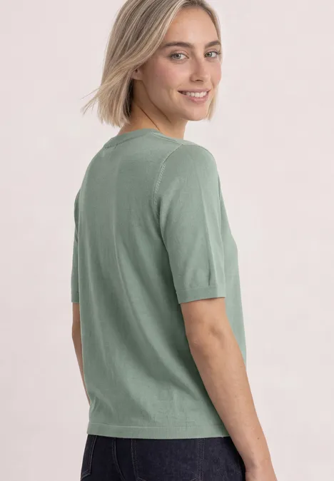 Kurzarm Pullover mit Rundhals in Unifarbe eucalyptus green Frau im hellgrünen T-Shirt zeigt Blick über die Schulter und lächelt.