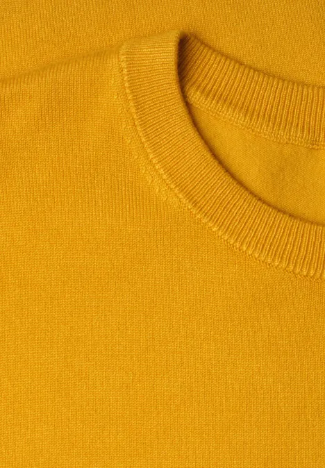 Nahaufnahme eines senfgelben Strickpullovers mit Rundhalsausschnitt.