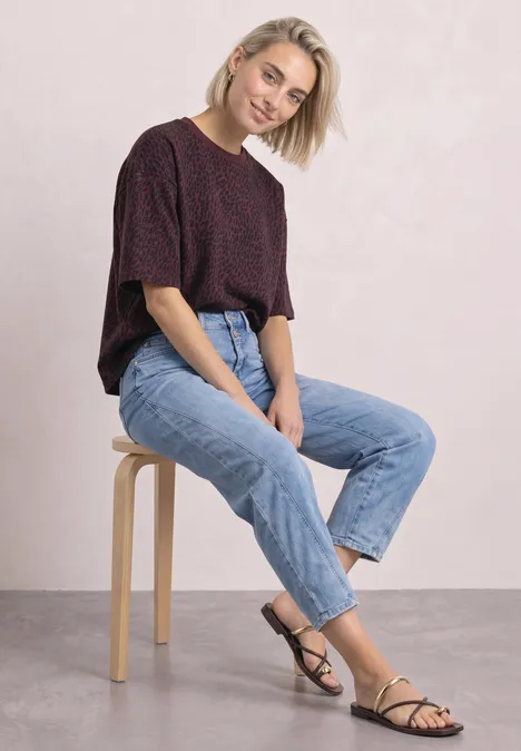Kurzarm Sweatshirt mit Rundhals rustic rouge Eine junge Frau sitzt lässig auf einem Hocker in Jeans und kurzem Oberteil, lächelt in die Kamera.