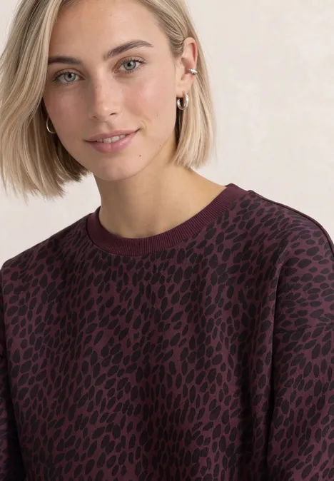 Kurzarm Sweatshirt mit Rundhals rustic rouge Eine Frau mit blonden Haaren trägt einen bordeauxroten Pullover mit schwarzem Animal-Print.