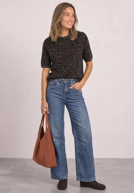Jacquard Pullover mit Rundhals und Leo-Muster molten earth Frau mit schwarzem Shirt, weitem Jeans und brauner Tasche, steht lächelnd vor neutralem Hintergrund.