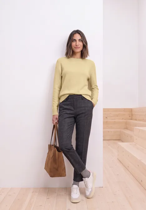Trui met lange mouwen en boothals sunbeam yellow mel. Frau in hellem Pullover, dunklen Hosen und weißen Sneakern steht lässig mit brauner Tasche in modernem Raum.
