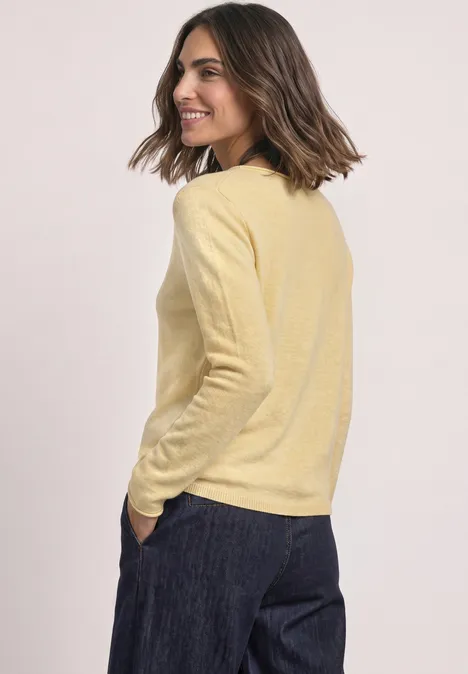 Pullover mit Boat Neck und Rollkanten sunbeam yellow mel. Eine Frau in gelbem Pullover und dunkler Hose blickt lächelnd seitwärts.