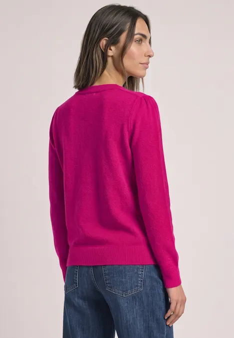 Femme vue de dos portant un pull fuchsia et un jean