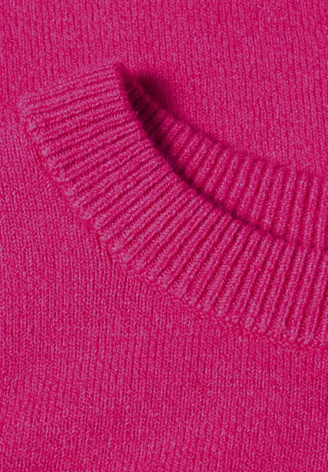 Gros plan d'un pull tricoté rose vif avec un col ras du cou côtelé