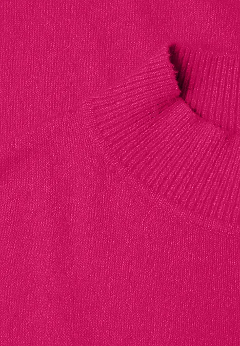 Close-up van een felroze gebreide trui met geribbelde hals en mouwboorden.