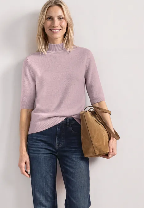 Kurzarm Pullover mit Turtle Neck quiet rose mel. Eine Frau in rosa Kurzarmpullover, Jeans und trägt eine braune Tasche, steht vor neutralem Hintergrund.