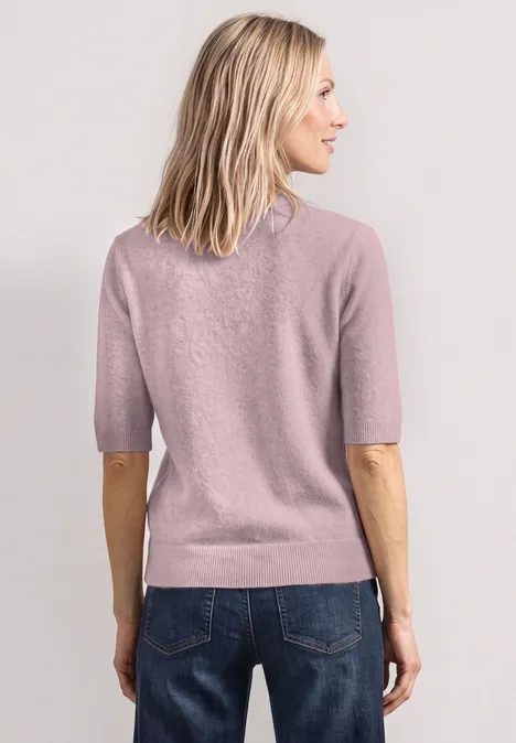 Kurzarm Pullover mit Turtle Neck quiet rose mel. Frau mit schulterlangem blondem Haar trägt rosafarbenen Pullover und Blue Jeans, von hinten fotografiert.