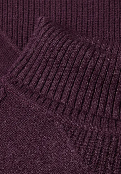 Nahaufnahme eines dunkelvioletten Strickpullovers mit geripptem Rollkragen