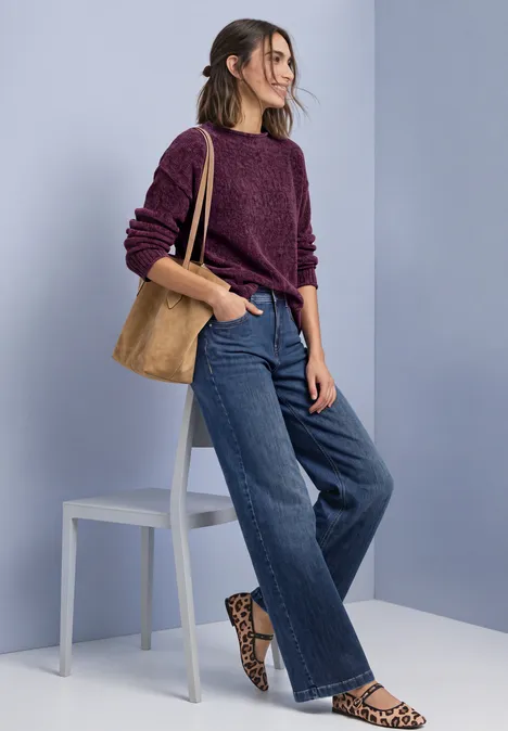 Chenille-Pullover mit U-Boot-Ausschnitt berry maroon Frau in lila Pullover, weiten Jeans und Leo-Slippern mit brauner Tasche vor hellblauem Hintergrund.