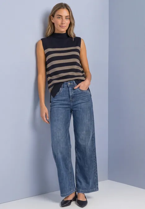 Pullunder mit Turtle Neck und Rollkanten indigo night Frau im ärmellosen gestreiften Top, weiten Jeans und schwarzen Ballerinas vor schlichtem Hintergrund.