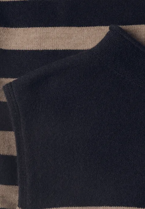 Pullunder mit Turtle Neck und Rollkanten indigo night Schwarzes ärmelloses Stricktop liegt auf einem gestreiften Pullover in Beige und Schwarz.