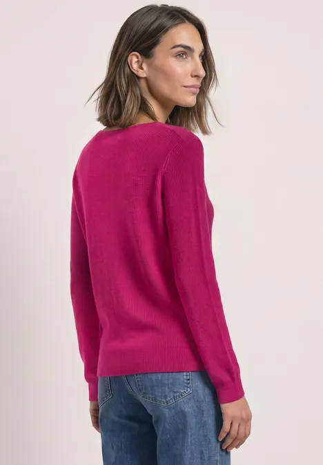 Langarm Pullover mit V-Ausschnitt magenta dream Frau von hinten in pinkem Pullover und Jeans vor hellem Hintergrund.