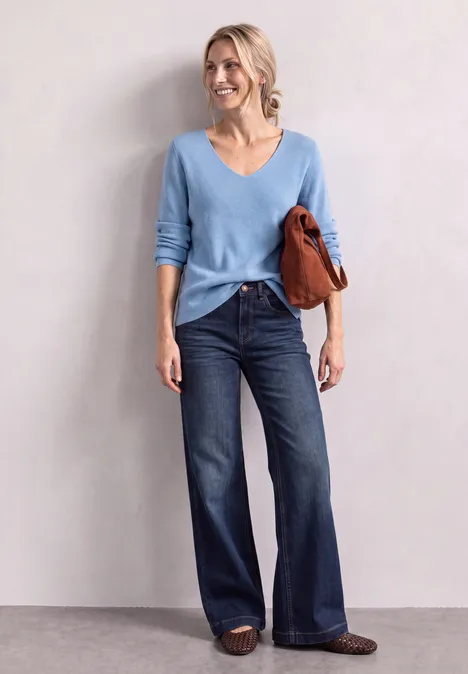 Langarm Pullover mit V-Ausschnitt northern blue Frau in hellblauem V-Ausschnitt-Pullover und weiten Jeans, trägt braune Sandalen und eine rostbraune Tasche.