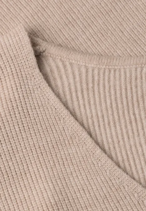 Gros plan d’un pull en maille beige côtelée avec col en V.