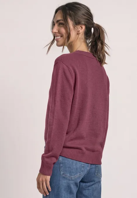 Langarm Pullover mit V-Ausschnitt dark clouded blush Frau in bordeauxrotem Pullover und Jeans von hinten, lächelnd seitlich blickend.