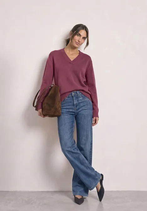 Langarm Pullover mit V-Ausschnitt dark clouded blush Frau trägt weinroten Pullover, weite Jeans und Tasche